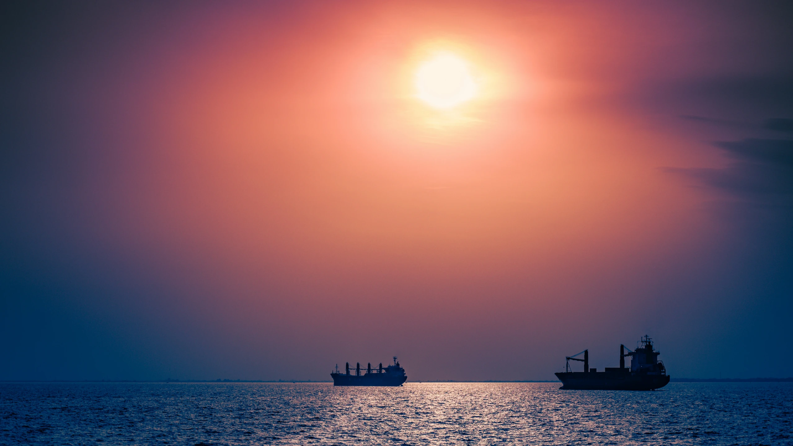 a ship that is floating in the ocean with the sun going down