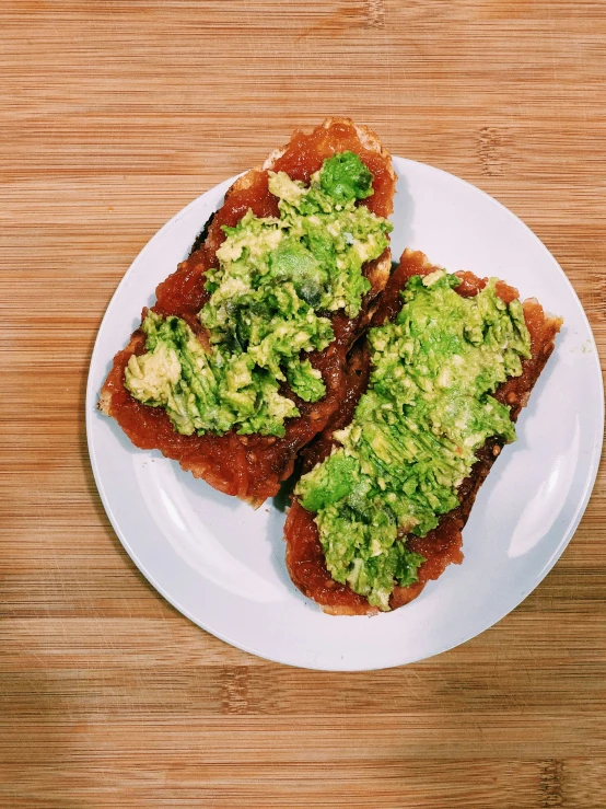 three pieces of toast covered in pesto sitting on top of a plate