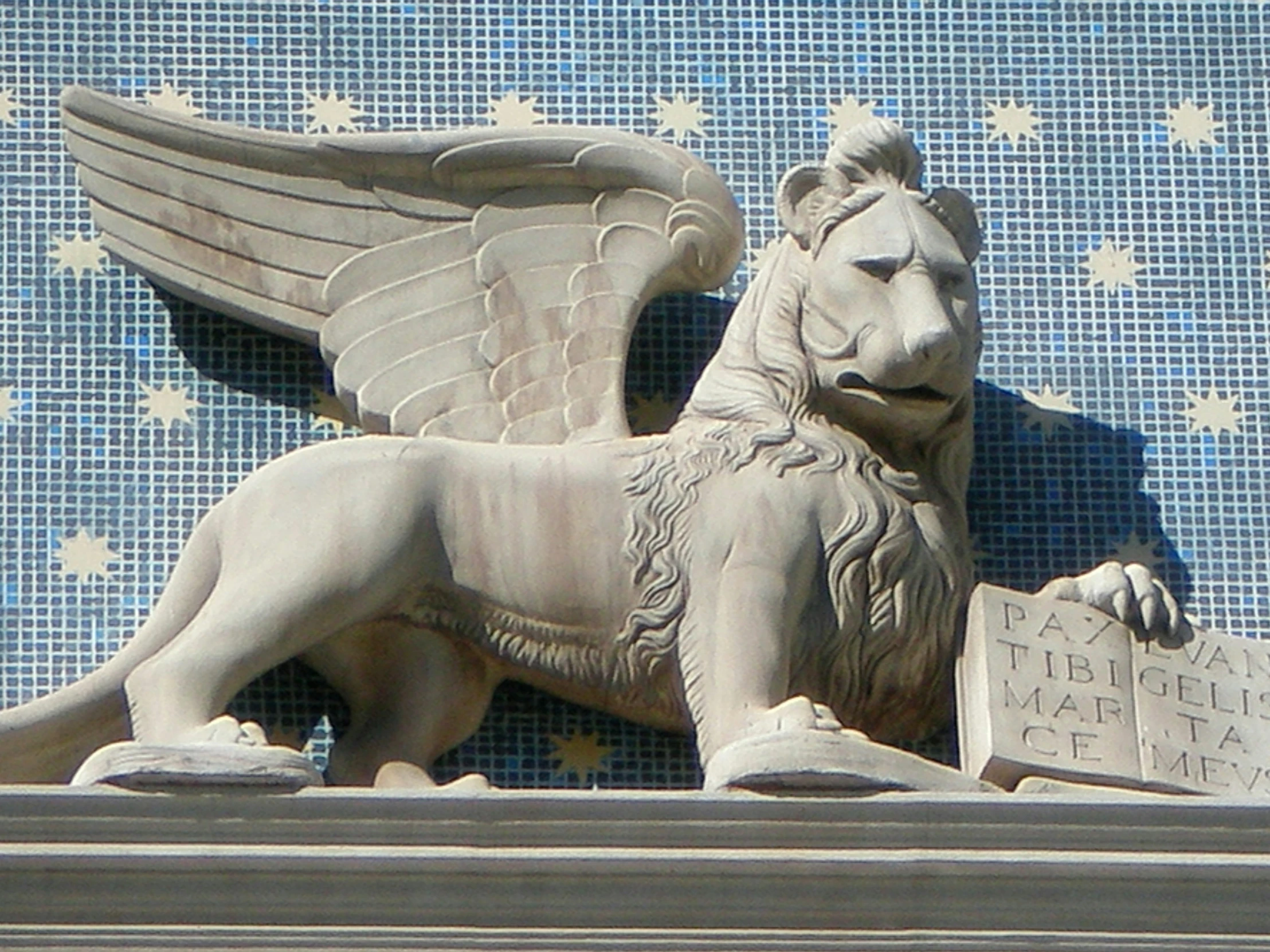 a sculpture of a lion with wings holding a book