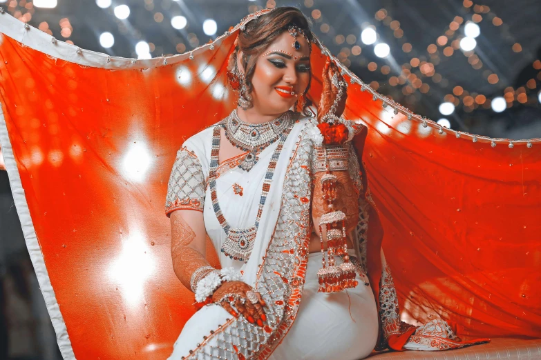 a woman in white clothing posing with an orange cloth