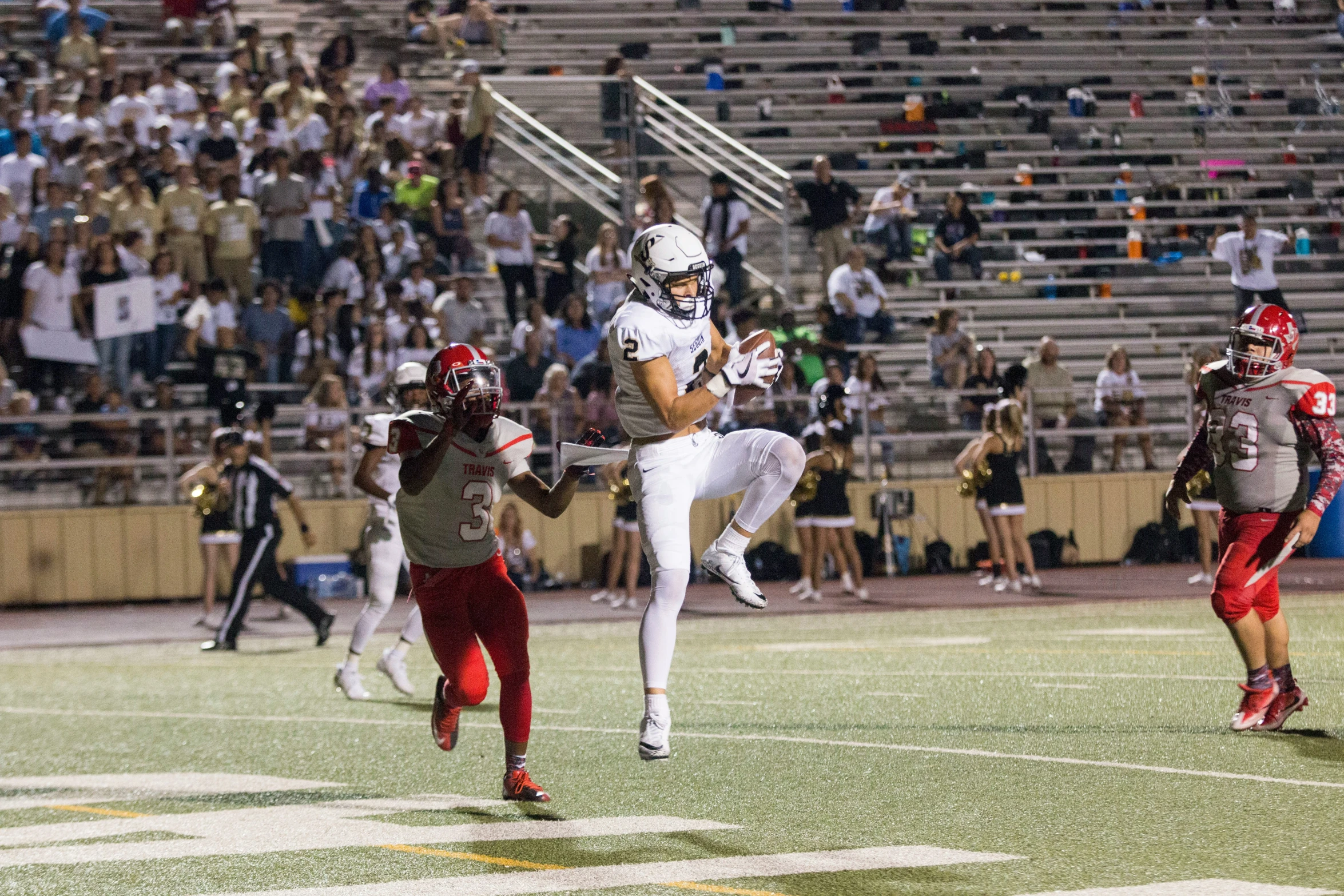 football player jumping up for a high kick in front of a crowd