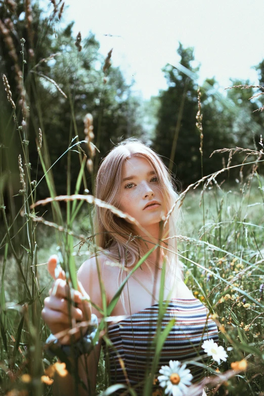 a young blonde girl in striped top sitting in tall grass