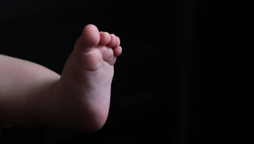 the front foot of a baby that is being held by a woman's hand