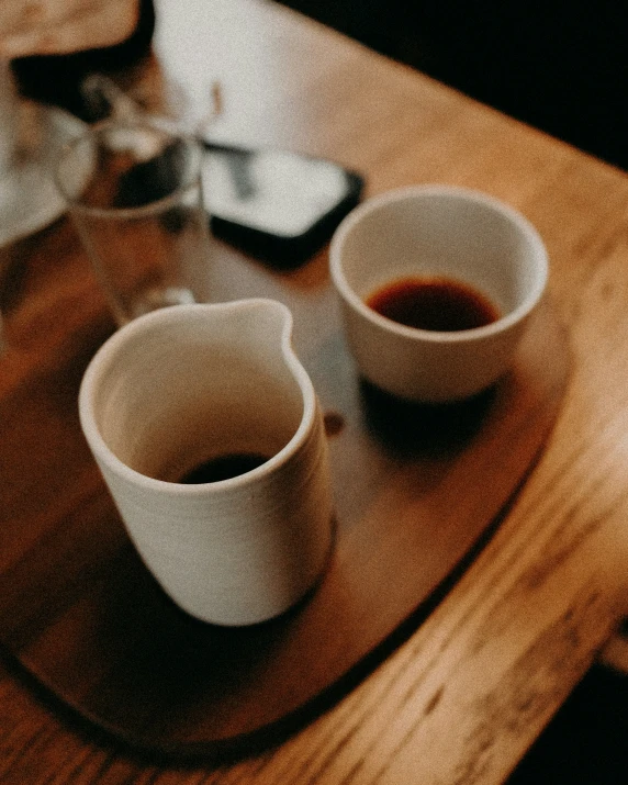 two cups of coffee sitting on a wooden table