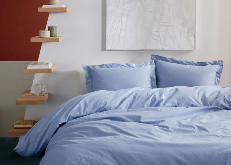 a bedroom with blue bedding and a white picture on the wall