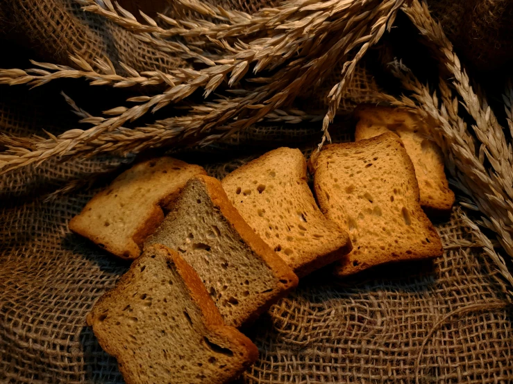 sliced breads and stalks of wheat on top of burlow