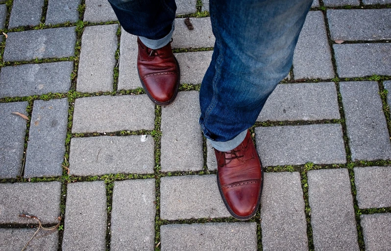 a man's feet standing on a brick sidewalk