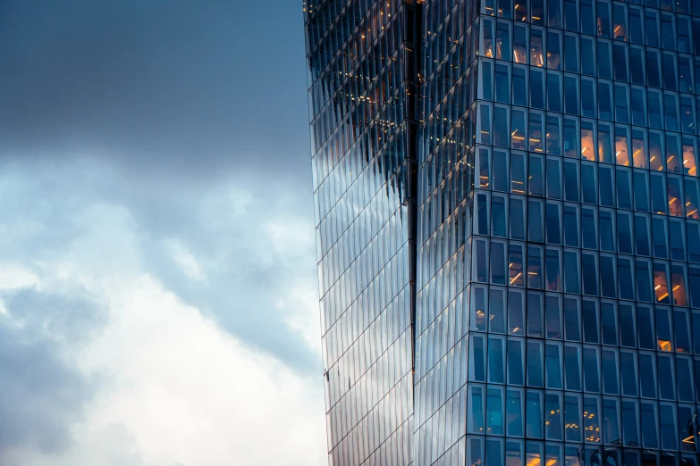 a tall building with windows and clouds behind it