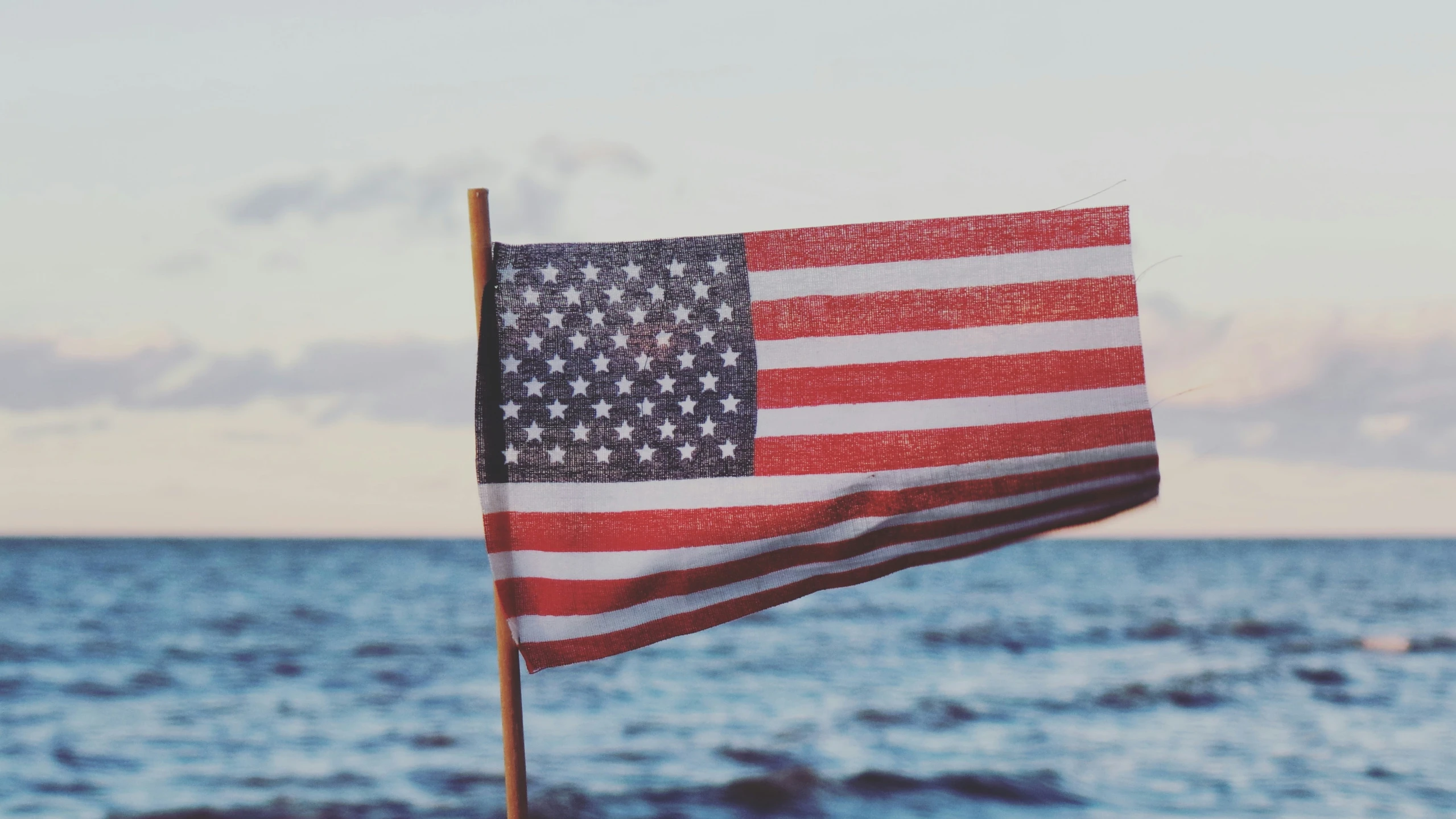 a patriotic flag blowing in the wind at the beach