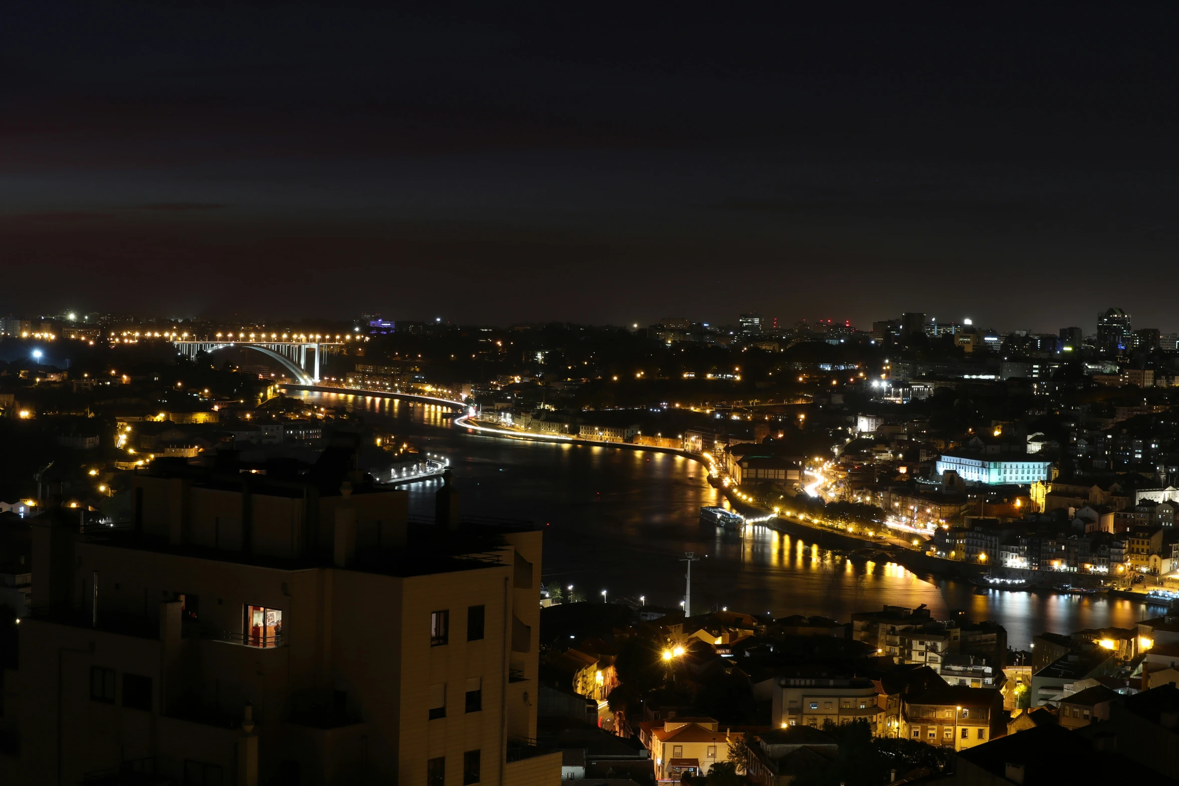 a view of a river running between a building and some lights at night