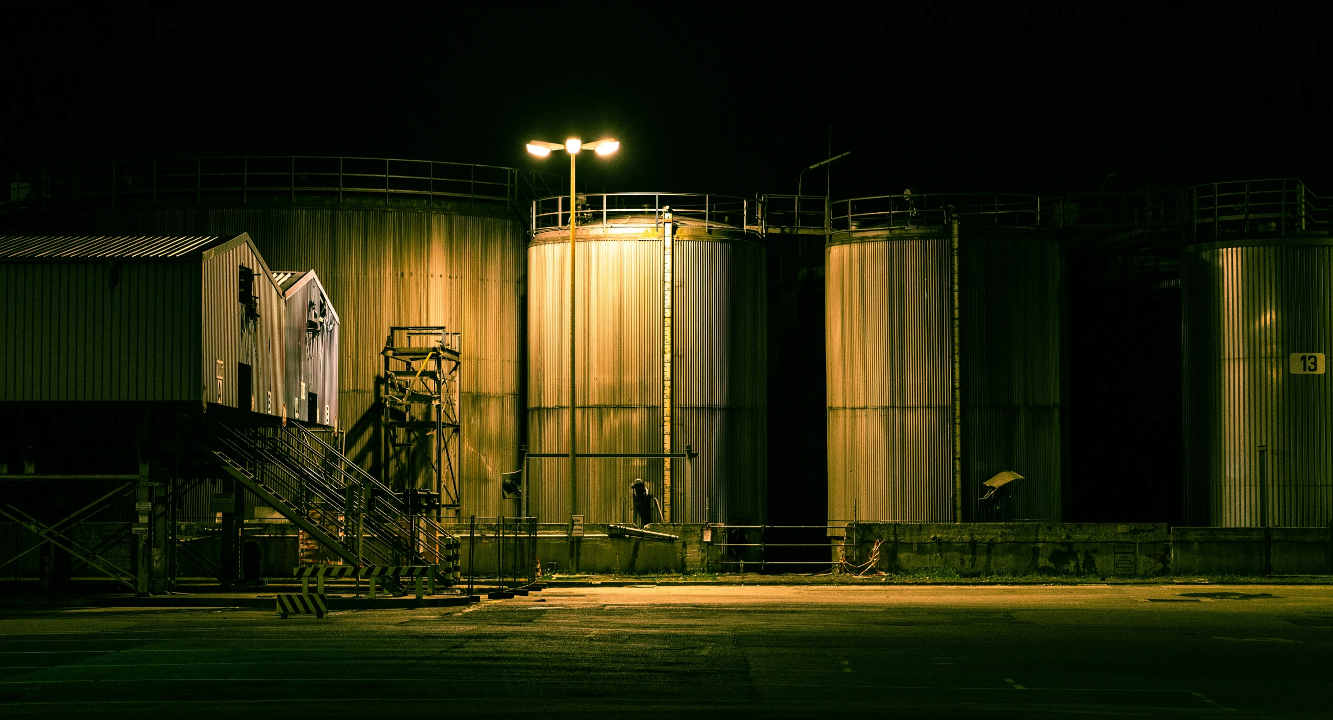 some lights are shining on several silos at night