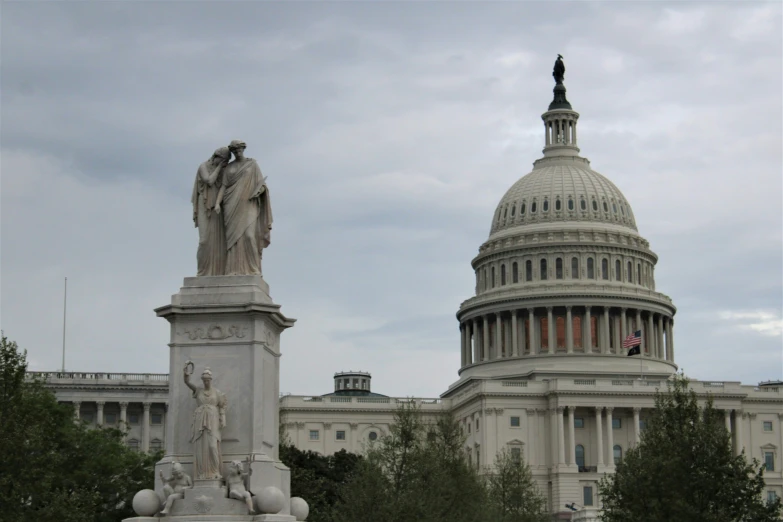 the capitol building is behind a statue on the corner