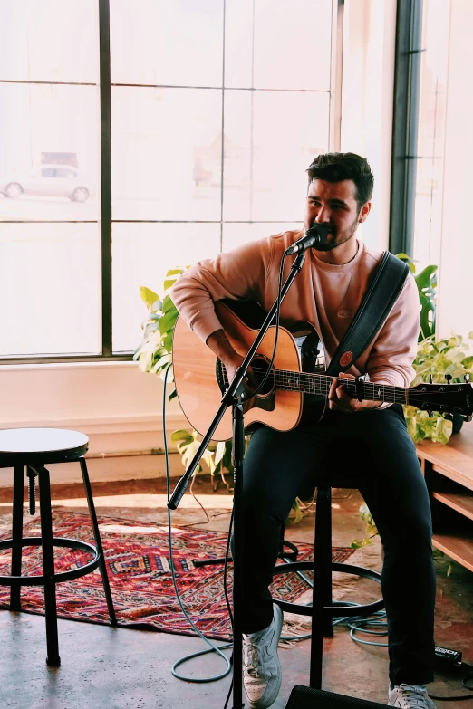 the man is sitting in front of the microphone while he plays his guitar