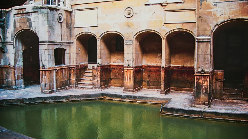 an open courtyard with some columns around a small pond