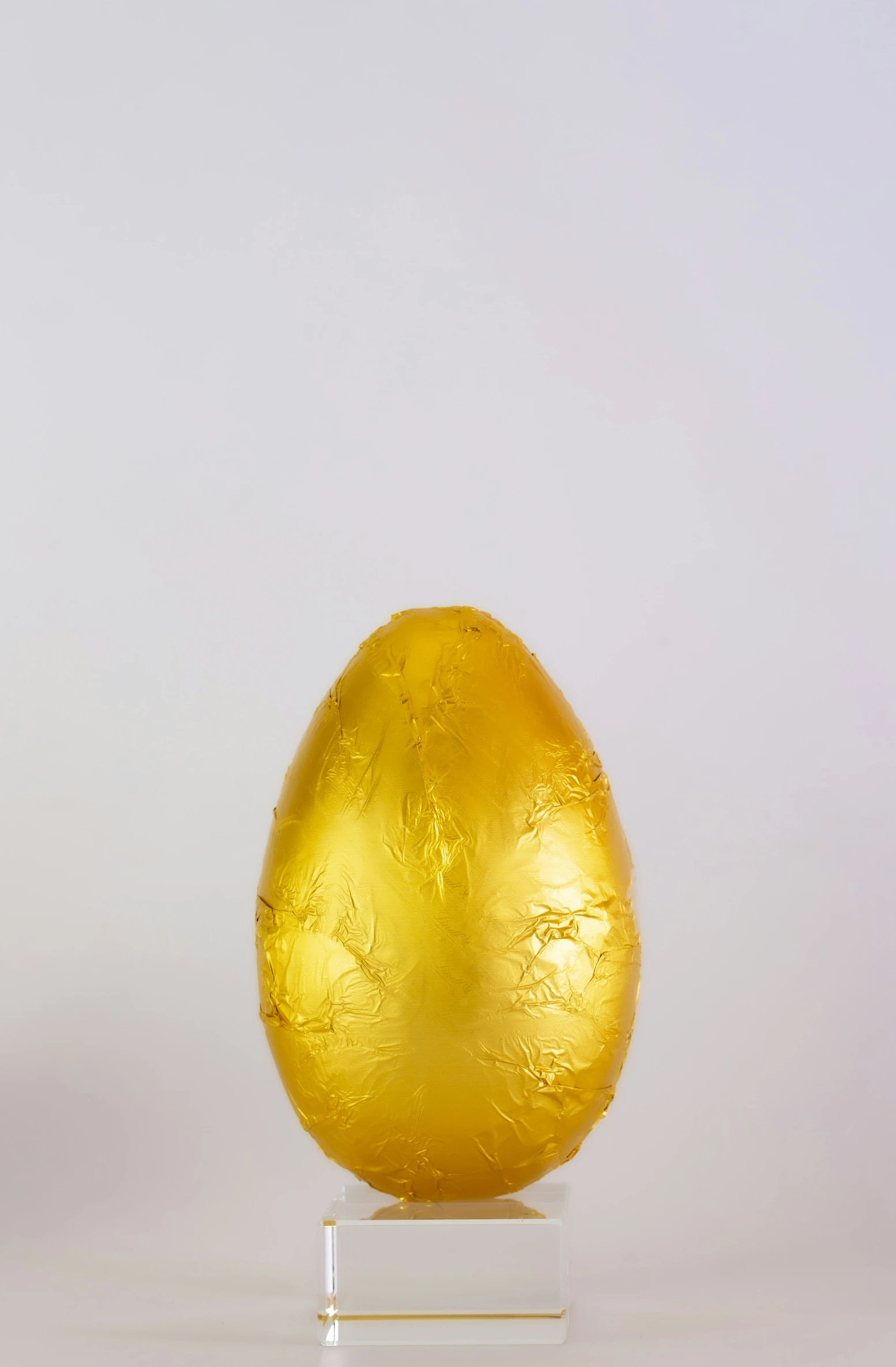 an ornate golden egg sitting on a clear stand