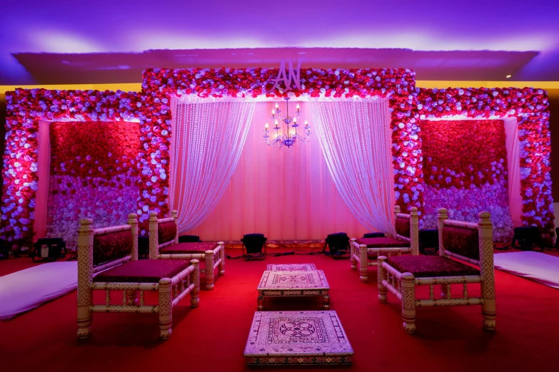 a stage with chairs and curtains is decorated with artificial flowers