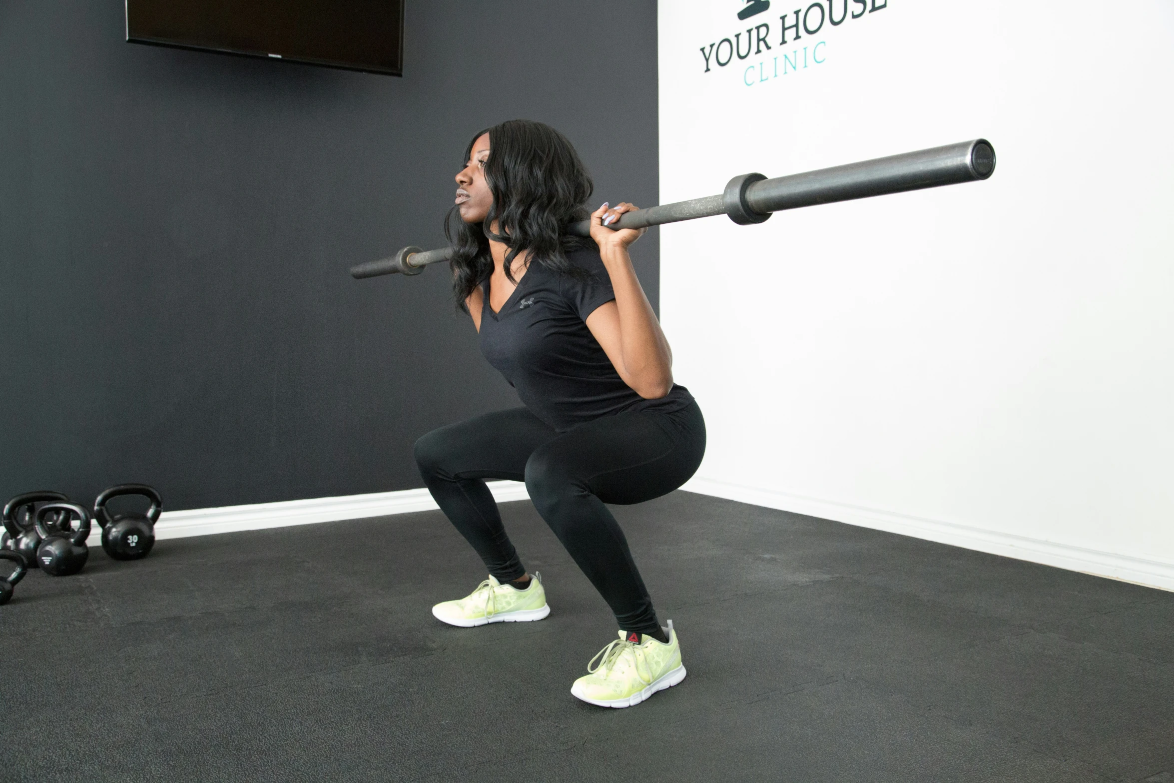 a woman standing in front of a wall with a black barbell