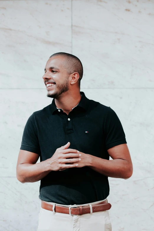 a man wearing a black shirt and beige pants, smiling