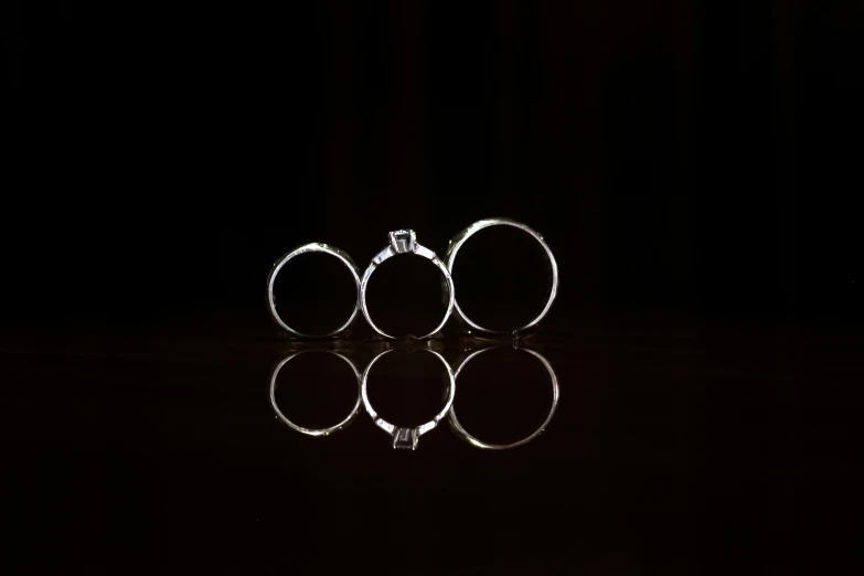 four silver rings are shown on a black background