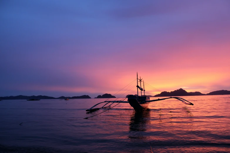 a boat floating in the water at sunset