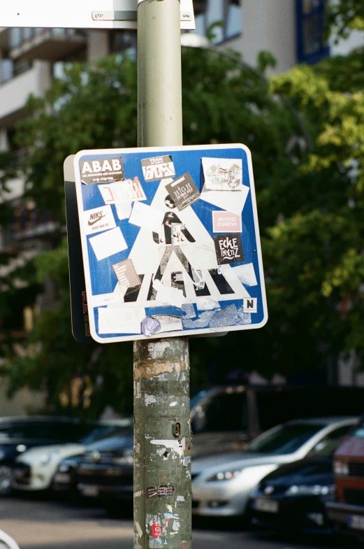 a street sign with stickers and cars parked on the side of the road