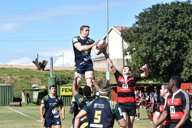 a rugby player is jumping high to make a s as another player looks on