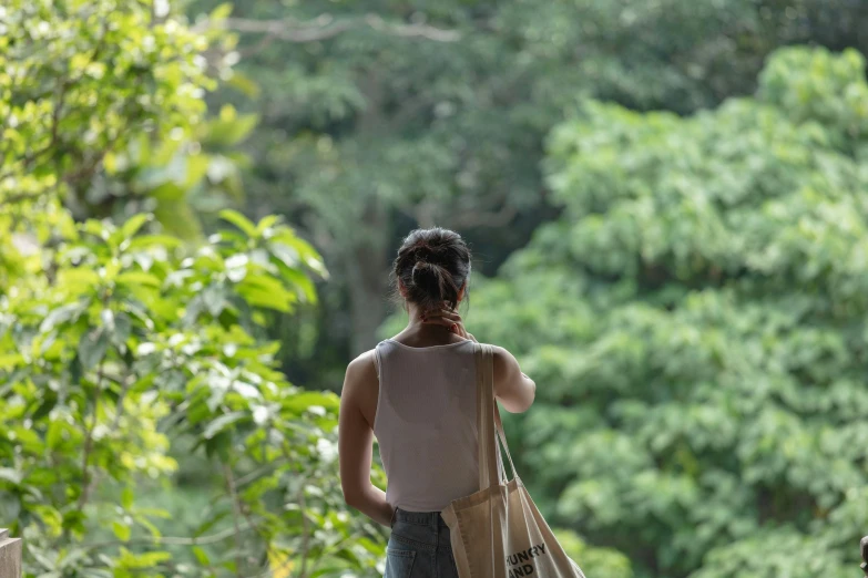a woman is holding two bags and walking along the woods