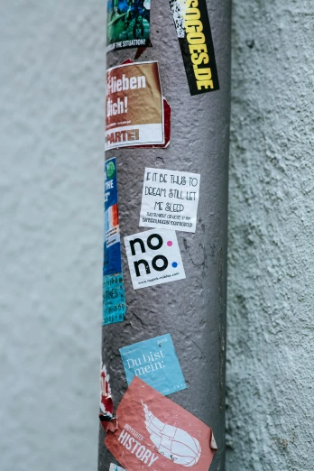 the street pole is adorned with stickers and other things