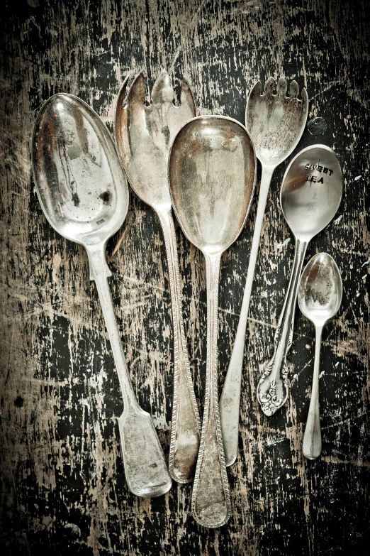a set of old fashioned metal utensils on a worn wood surface