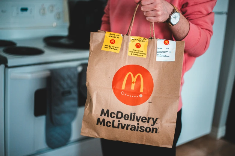 a person holding a brown bag with a mcdonald's ad on it