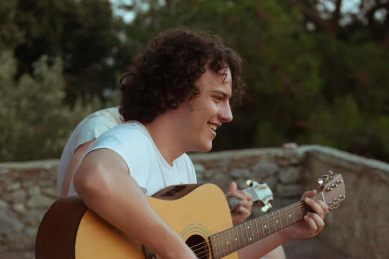 a young man is playing the guitar outside