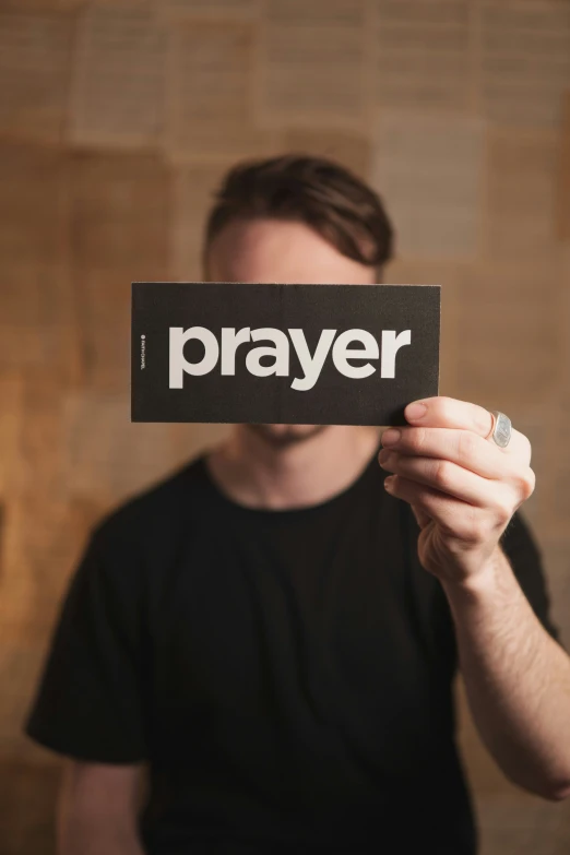 a person holding up a prayer card to the camera