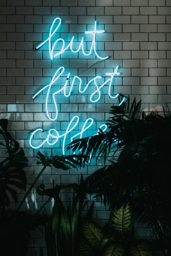 a wall with plants and a neon sign that says, bout fruiquet coffee