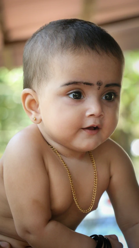 a baby wearing a chain with a small ring at its neck