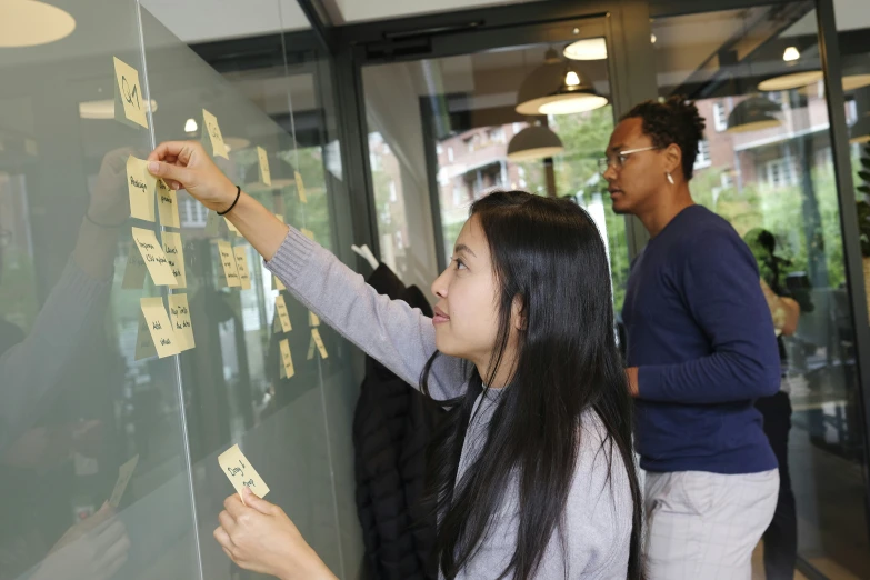 two people working with post - it notes on the glass door