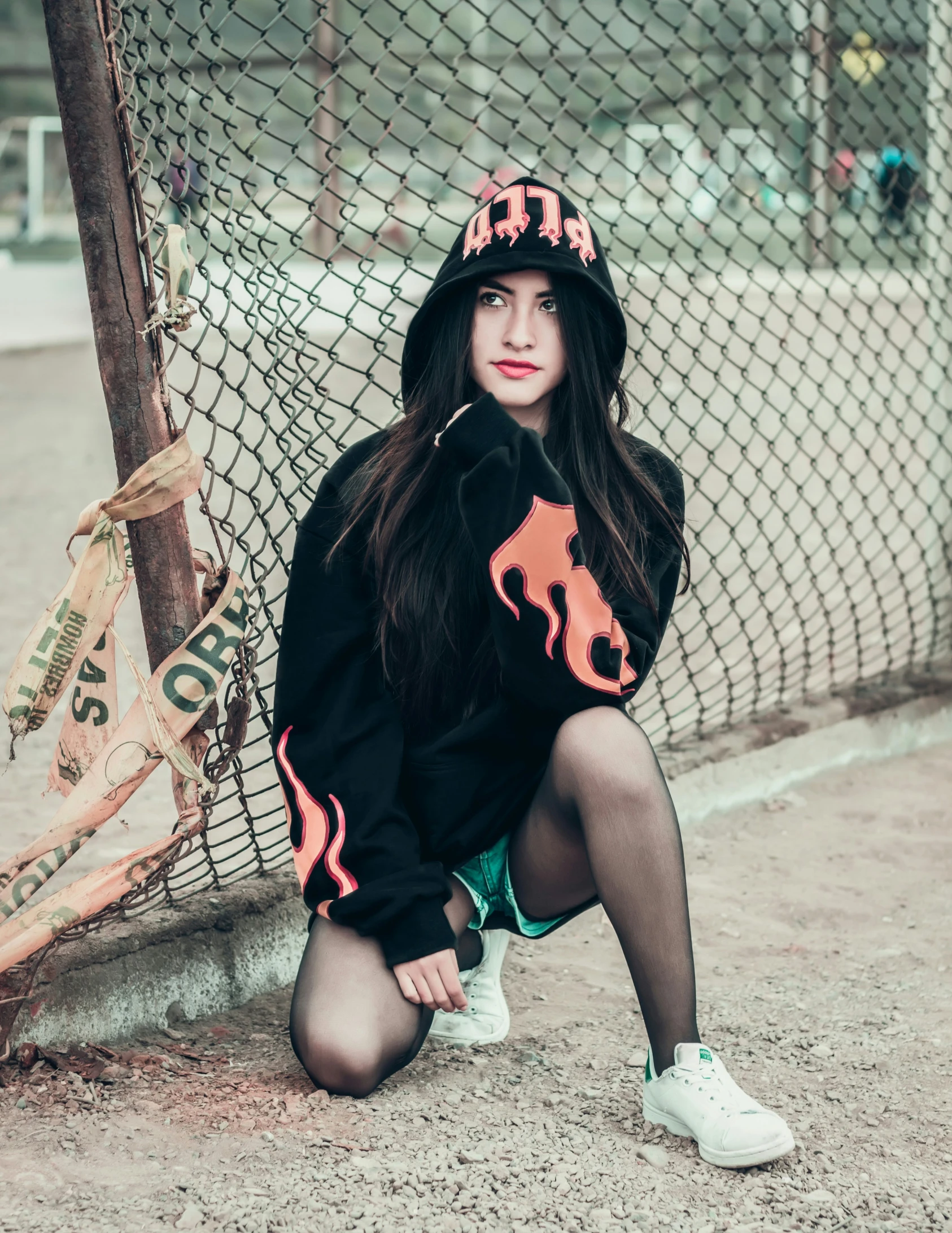 a woman sitting on a fence wearing a baseball cap