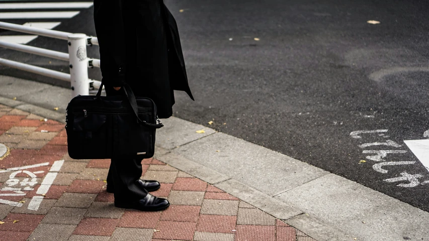 a person standing on a street corner with a handbag