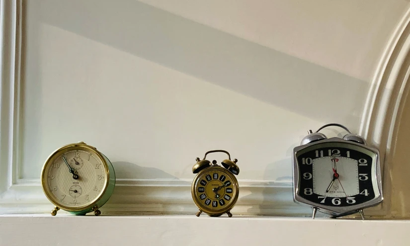 three clocks are displayed on a shelf next to each other