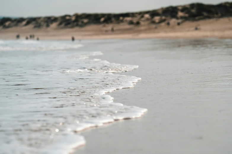 several people are walking in the water and playing on the beach