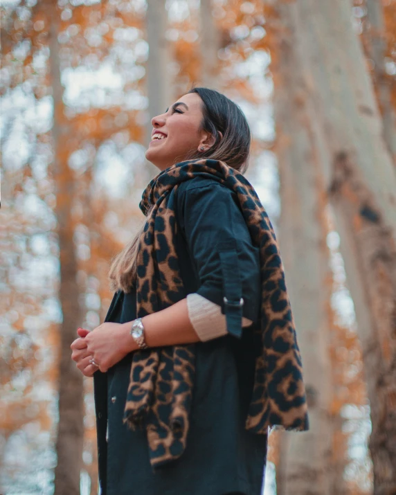 a woman standing in the woods wearing a scarf