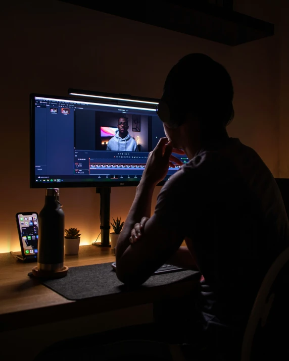 a person sitting at a table with a computer monitor