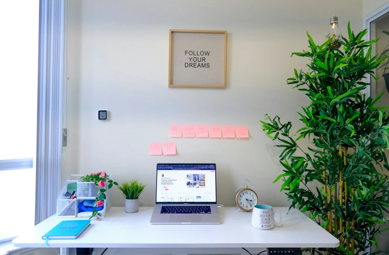 an office with white desk and a blue laptop on it