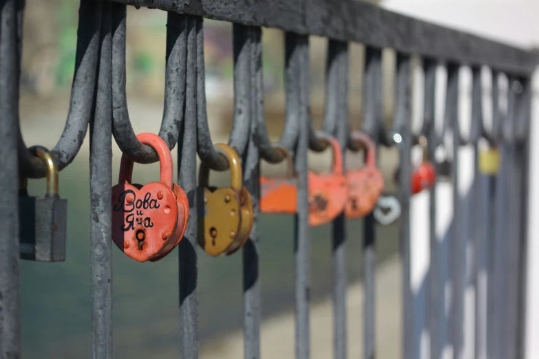 padlocks are hanging down the side of a fence