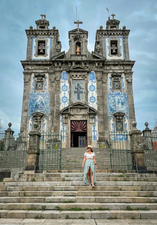 a woman in white top standing outside a large building