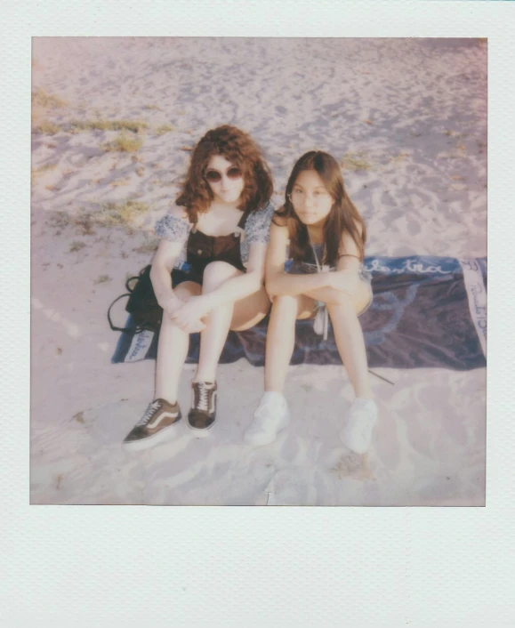 two women are sitting together on a blanket