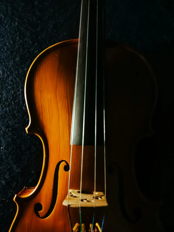 an old violin leaning up against a black wall