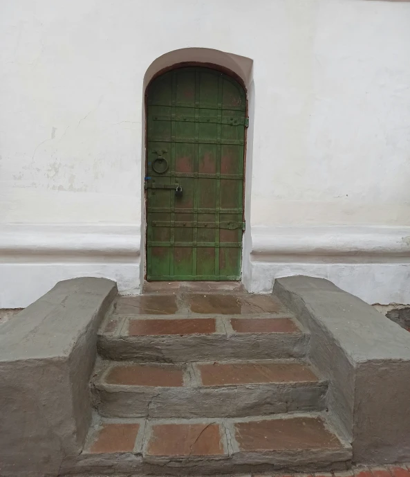 a green door sits on the front steps to a white building