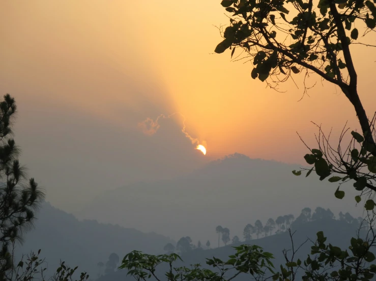 a setting sun surrounded by fog in a mountainside