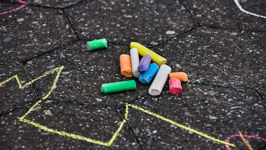 colored crayons are scattered near each other on the pavement