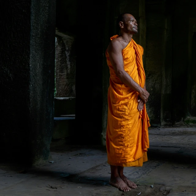 the monk is wearing his orange robes in an old building